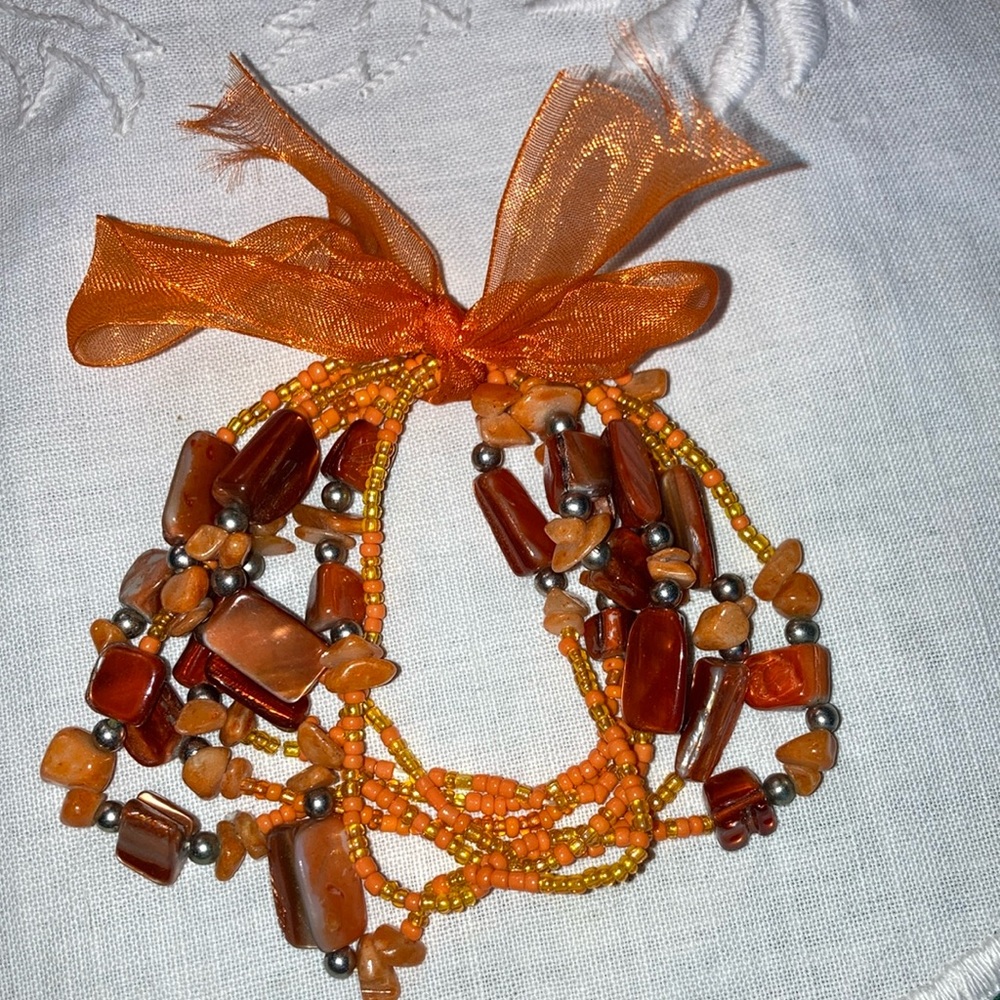 Set of five stretch bracelets with orange beads and seed beads.  $15